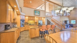 Una cocina amplia con armarios de madera, una isla central y un comedor con sillas de madera.
