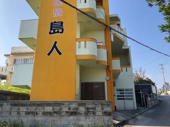 A multi-story building with a prominent yellow column featuring Japanese characters.