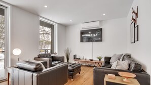 Ein modernes Wohnzimmer mit Ledersofas, einem Holztisch und einem an der Wand montierten Flachbildfernseher.