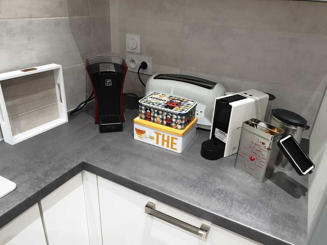 Una encimera de cocina con cafetera, tostadora y una caja con la etiqueta 'THE'.