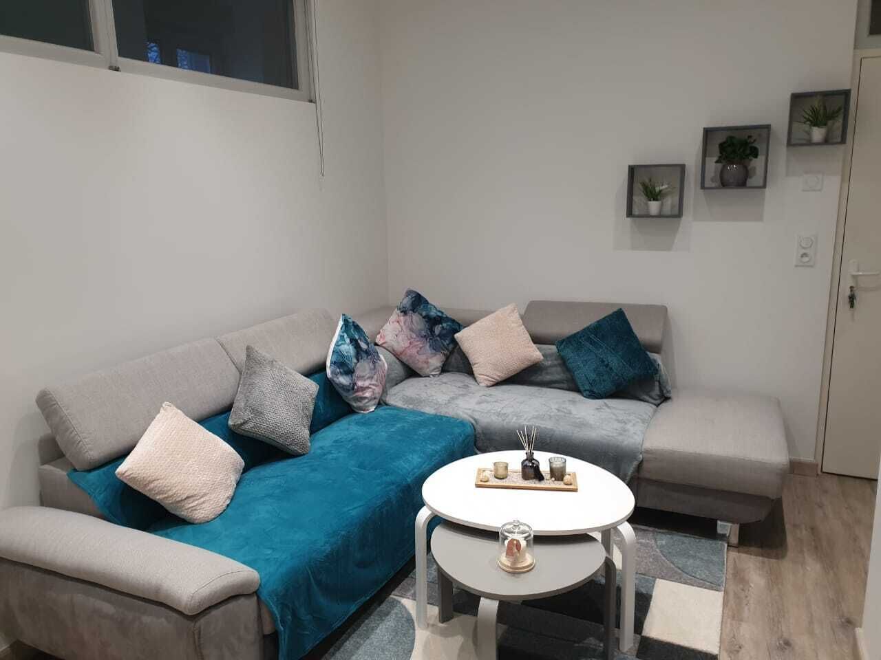 Een moderne woonkamer met een grijze zithoek, een ronde salontafel en een klein bijzettafeltje.