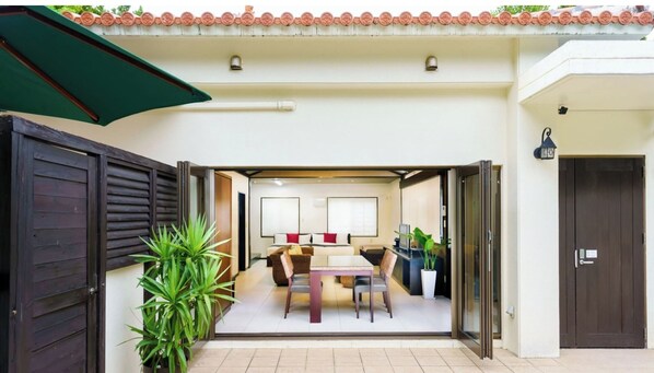 Une chambre d’hôtel avec un lit, une table à manger, des chaises, une plante en pot et une porte coulissante.