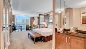 A hotel room with a large bed, a desk, a chair, a bench, a dining table, and a view of the city. - MGM Signature- Studio Workdesk Strip View Jacuzzi (Las Vegas)