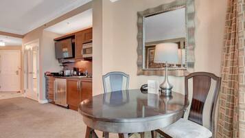 A dining area with a round table, two chairs, a mirror, and a lamp.