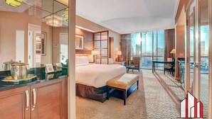 A hotel room with a large bed, a desk, a chair, a glass partition, and a view of the city. - MGM Signature-30-719 Strip View Jacuzzi Studio (Las Vegas)