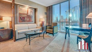 A hotel room with a large window, a sofa, a coffee table, and a desk with a chair. - MGM Signature-30-719 Strip View Jacuzzi Studio (Las Vegas)