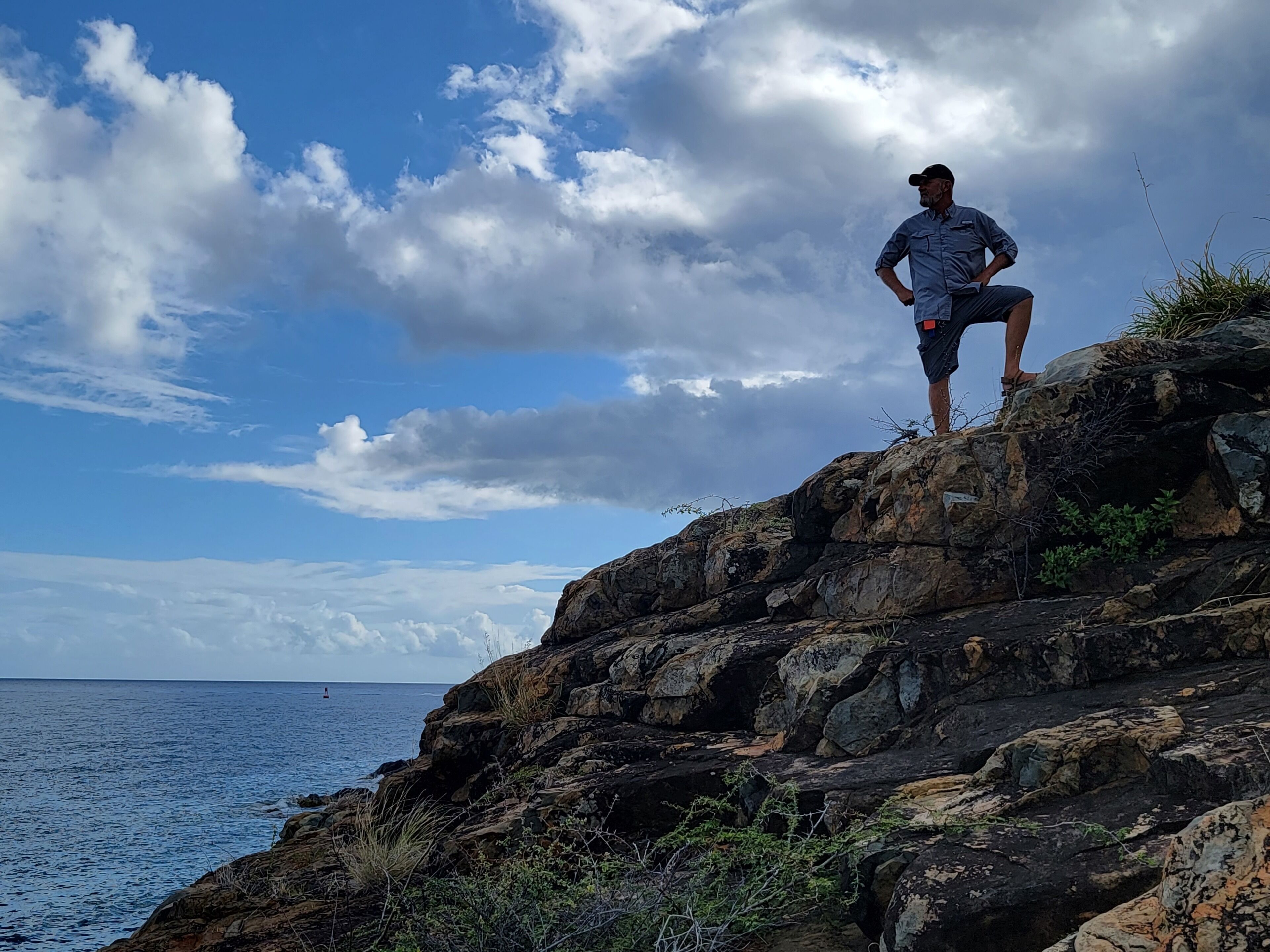 Un homme se tient debout sur une falaise rocheuse, surplombant la mer.