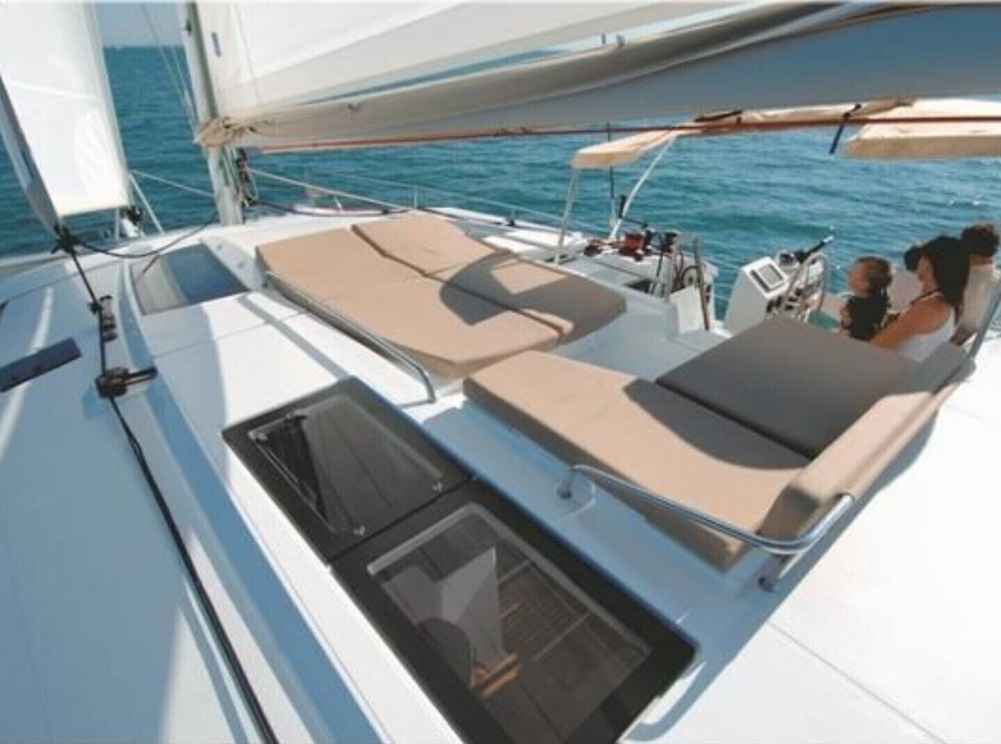 A sailboat with a sun deck featuring lounge chairs and a small enclosed area with a window.