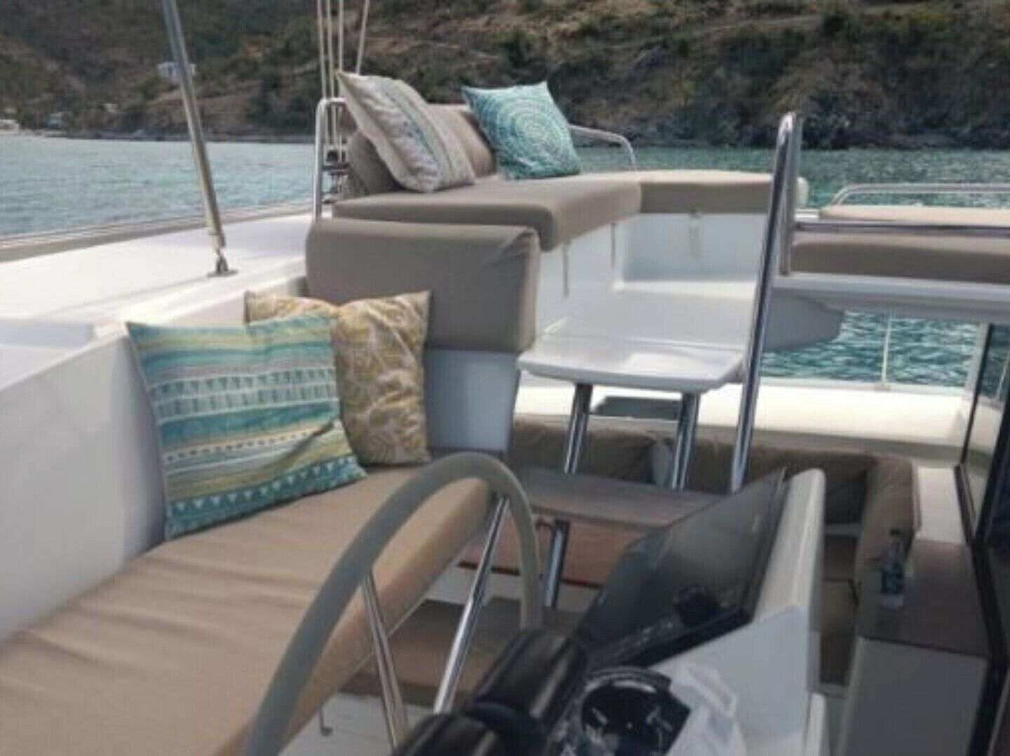 A boat interior with seating, a table, and a view of the sea.