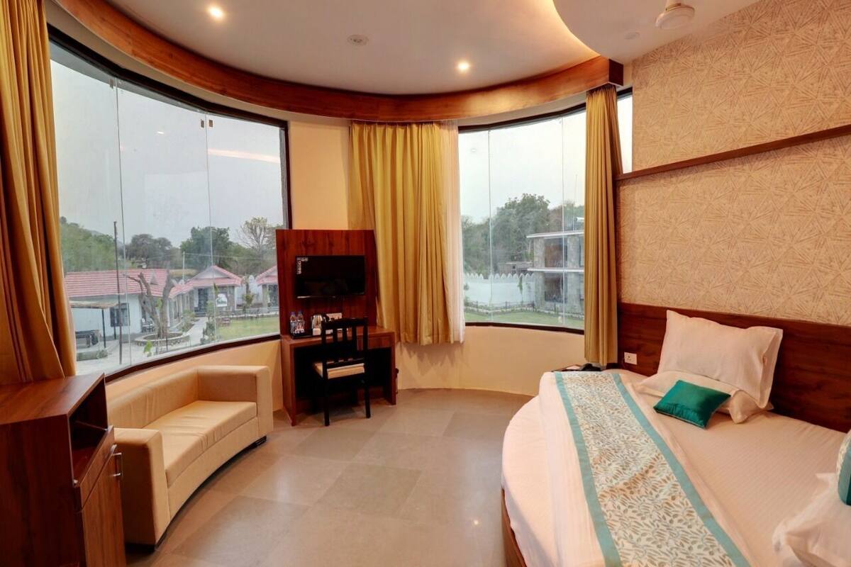 A hotel room with a bed, a sofa, a TV, and a desk.