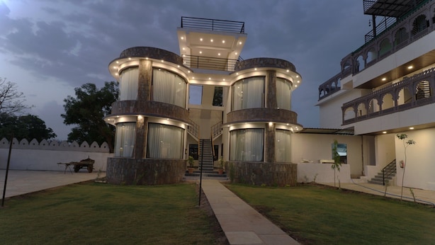 A modern building with a central staircase, multiple balconies, and a well-lit entrance. - Keshav Resort (Udaipur)