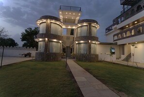 A modern building with a central staircase, multiple balconies, and a well-lit entrance. - Keshav Resort (Udaipur)