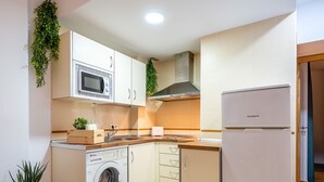 A compact kitchen with a washing machine, microwave, and refrigerator.