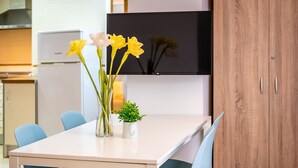 A dining table with chairs, a vase with flowers, and a small potted plant.