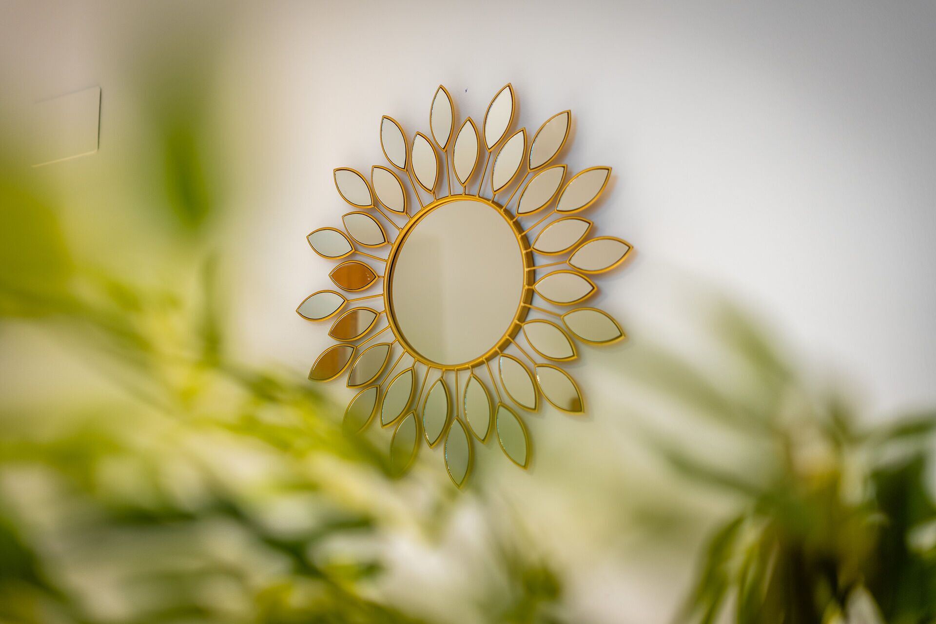 Espejo decorativo con forma de sol y marco dorado.