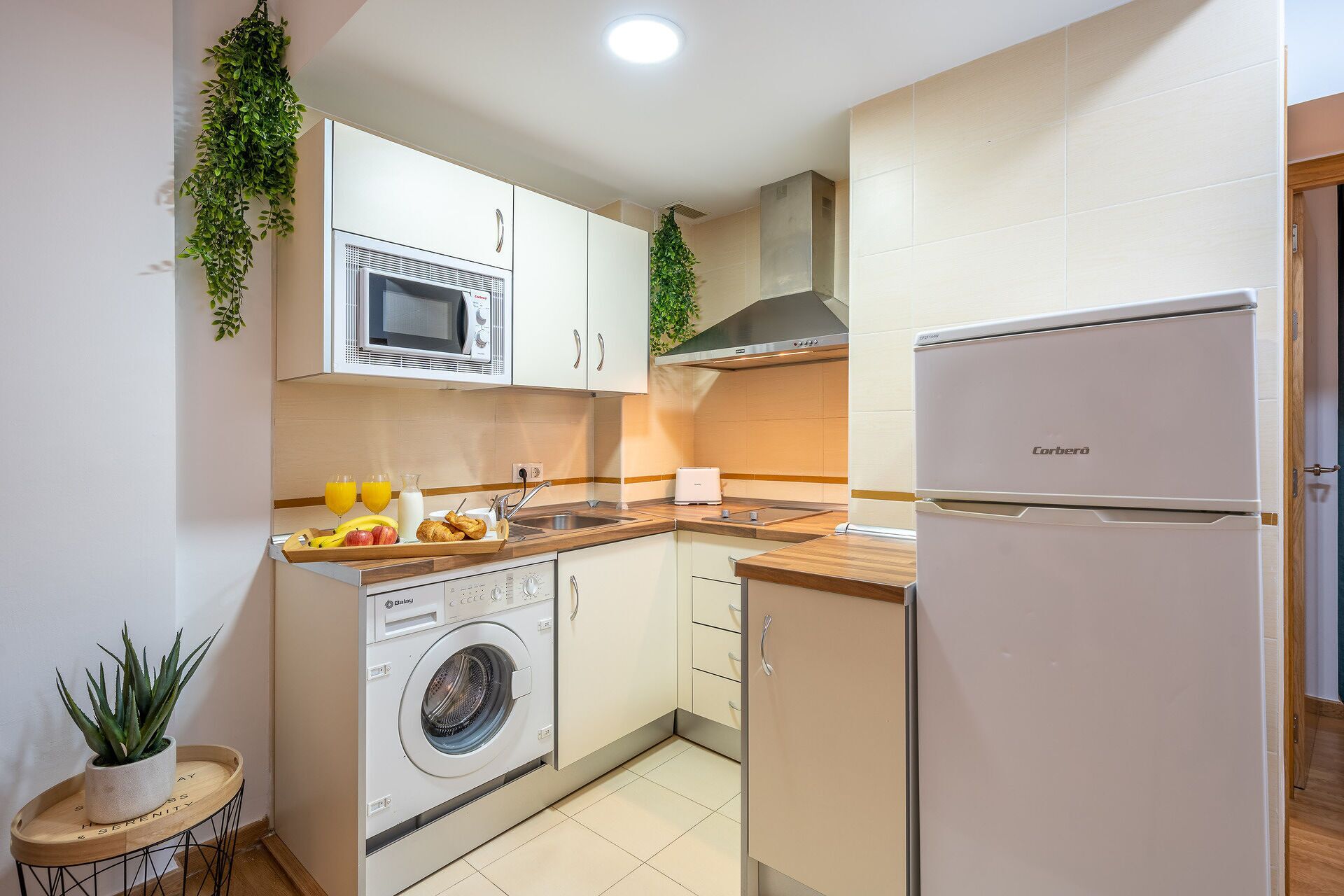 Cocina compacta equipada con microondas, tostadora, lavadora y refrigerador.