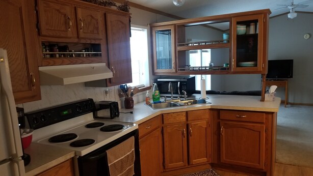 A kitchen with wooden cabinets, a stove, a microwave, and a sink.