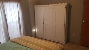 A bedroom with a bed, a wardrobe, and a door.