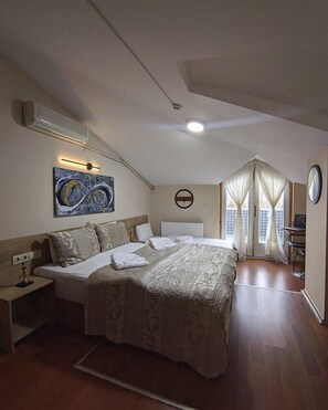 A bedroom with a large bed, a bedside table, a wall-mounted air conditioner, a ceiling light, a window with curtains, and a painting on the wall. - Rumeli Konak Butik Otel (Tekirdag)