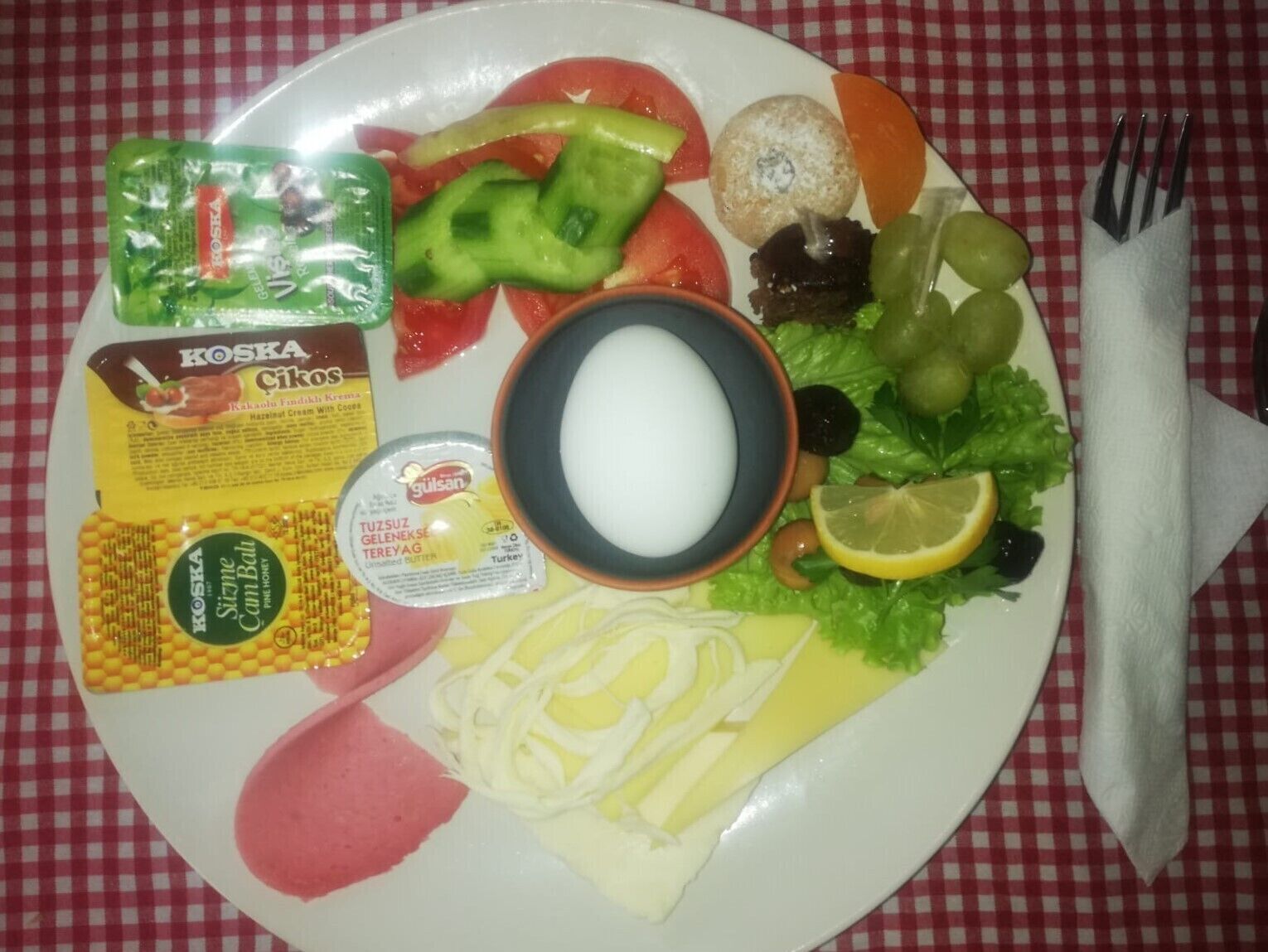 Une assiette contenant divers aliments, notamment du fromage, des légumes et des condiments.