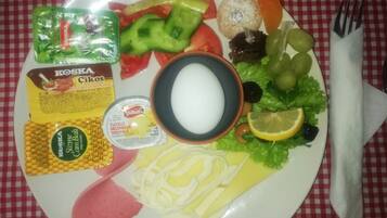 Une assiette contenant divers aliments, notamment du fromage, des légumes et des condiments.