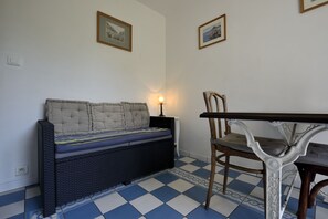 A room with a sofa, a dining table, and two framed pictures on the wall.