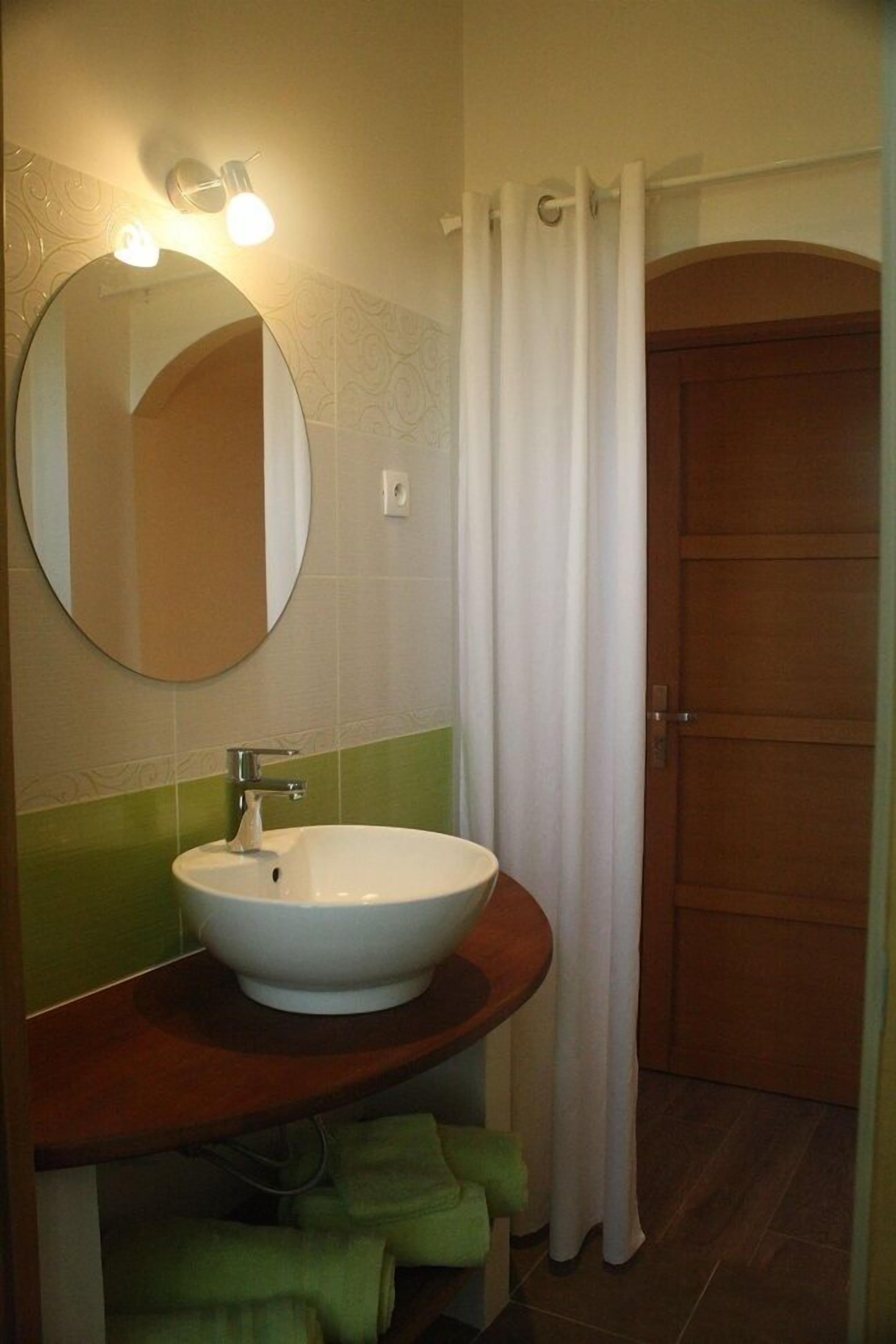 Un baño con un espejo redondo, un lavabo blanco y un mueble de tocador de madera.