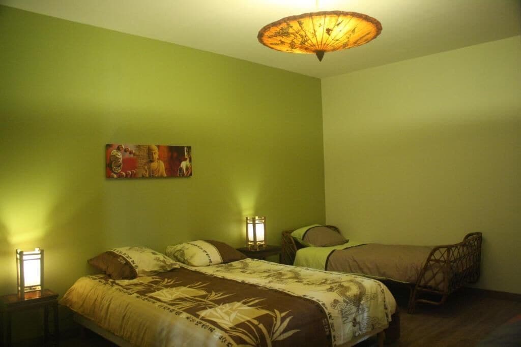 Une chambre avec deux lits, un tableau accroché au mur et un luminaire suspendu au plafond.