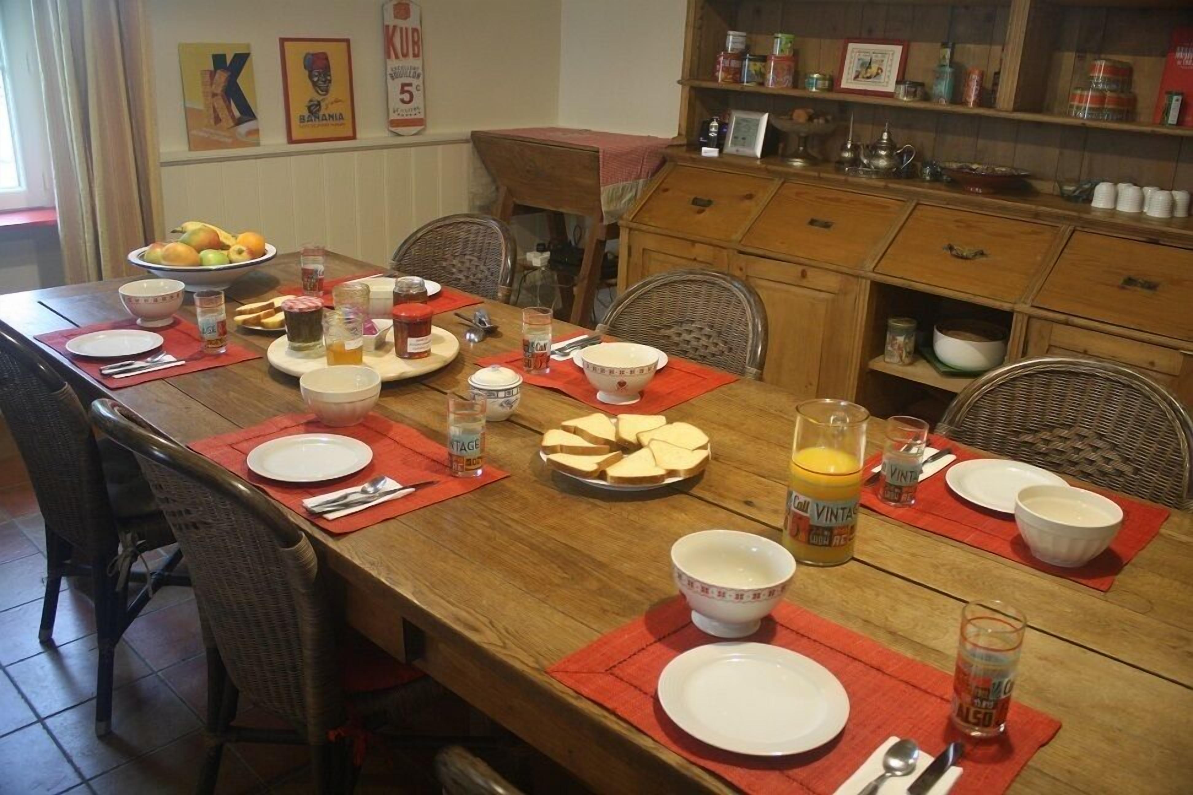 A dining table set with plates, bowls, and glasses, surrounded by wicker chairs.