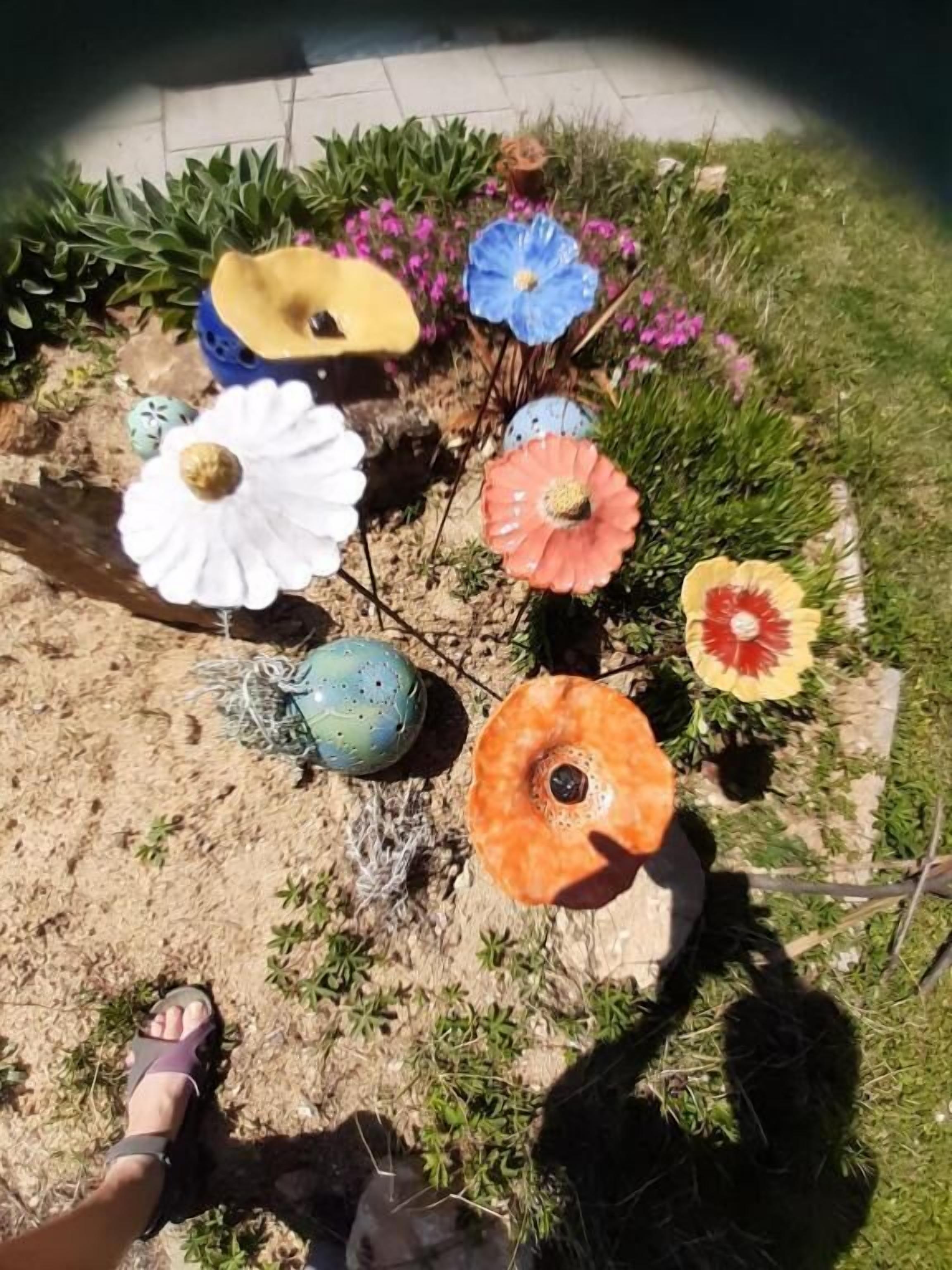 Um jardim com diversas flores artificiais coloridas e ovos decorativos.