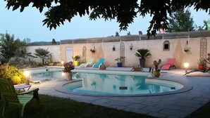 Zona de piscina con sillones de descanso y plantas en macetas.