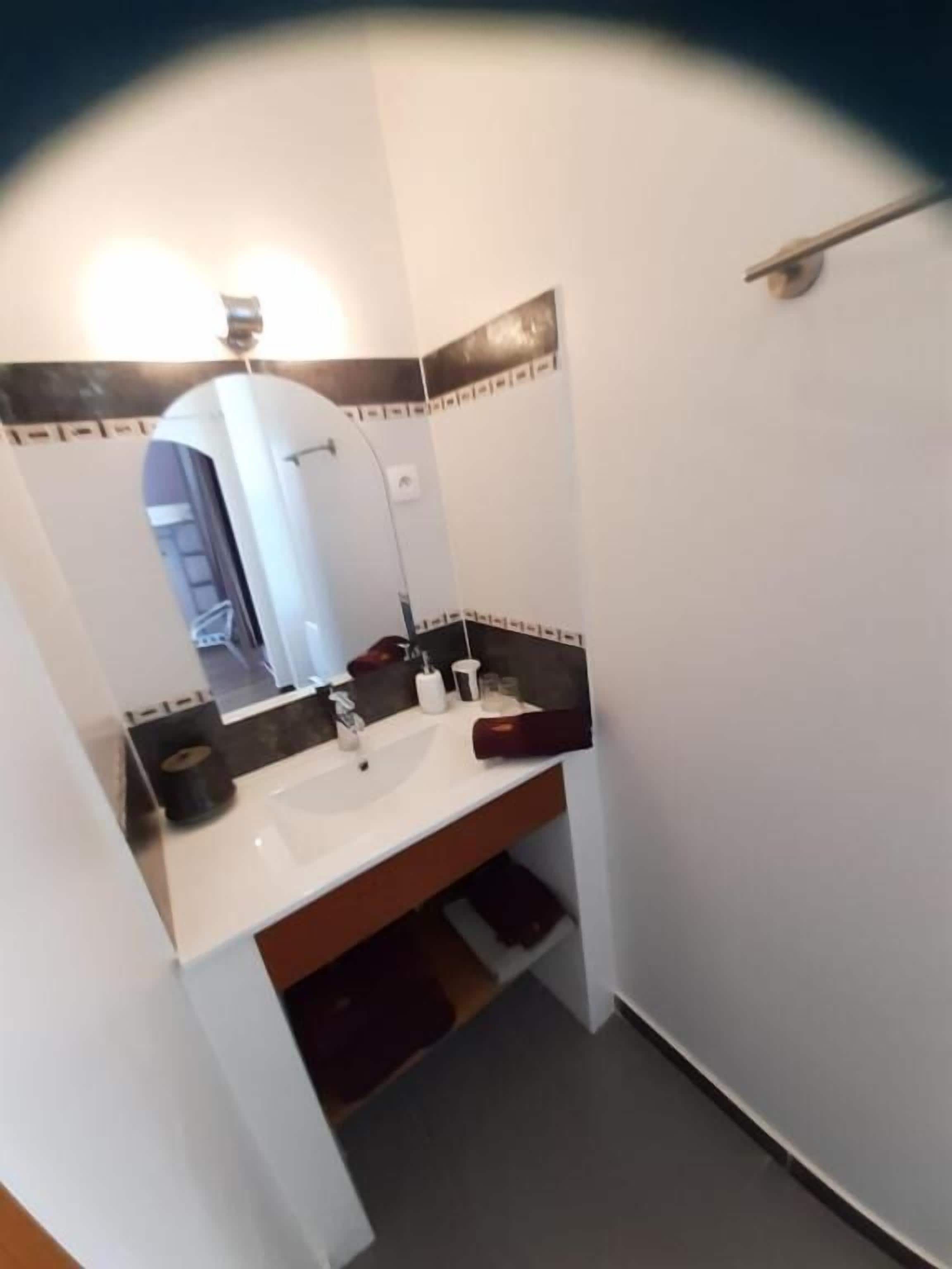 Ein Badezimmer mit einem weißen Waschbecken, einem Spiegel und einem Handtuchhalter.