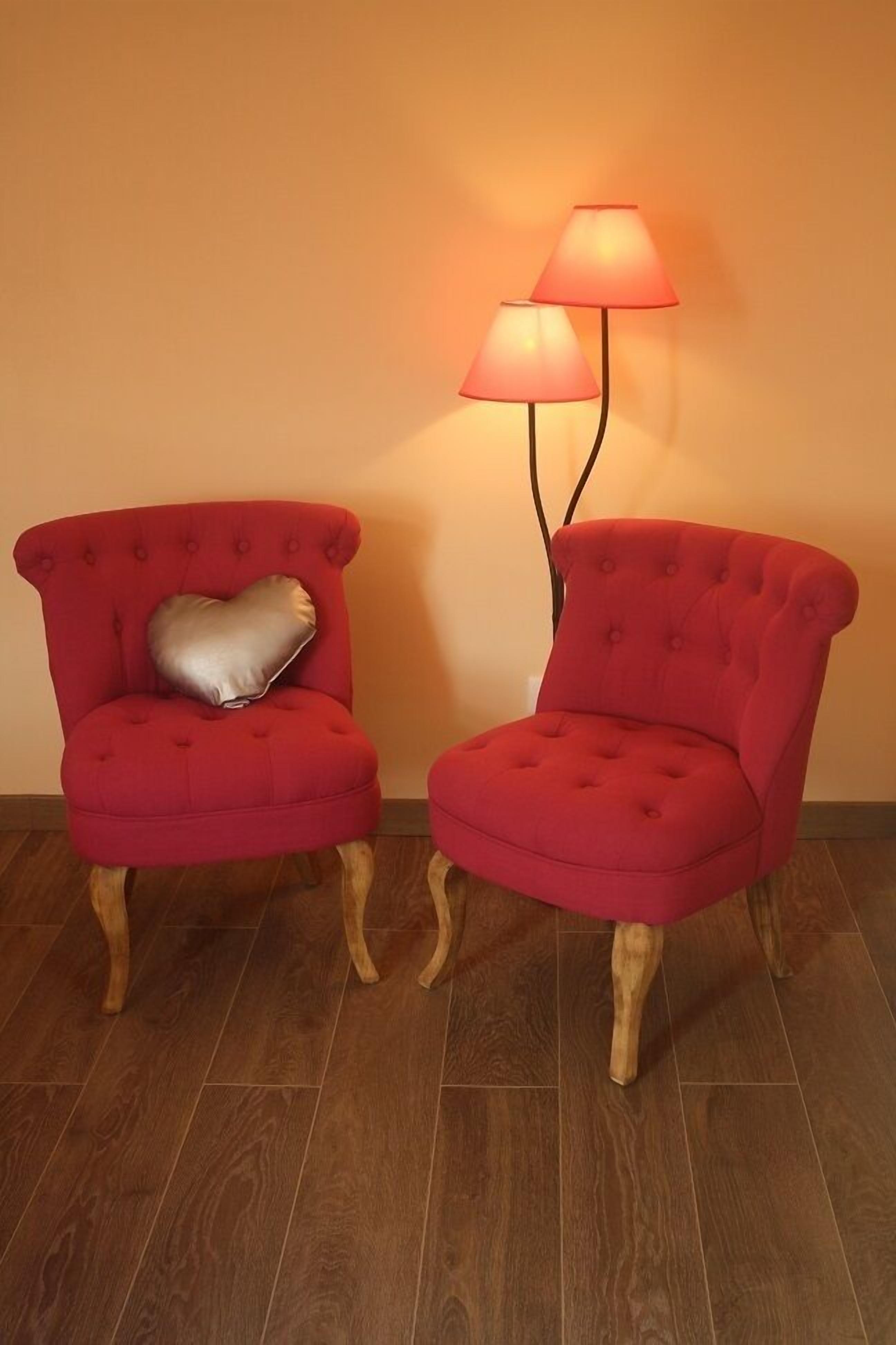 Two red upholstered chairs with wooden legs and a heart-shaped pillow on one.