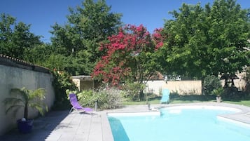 Una piscina al aire libre de temporada, sillones reclinables de piscina