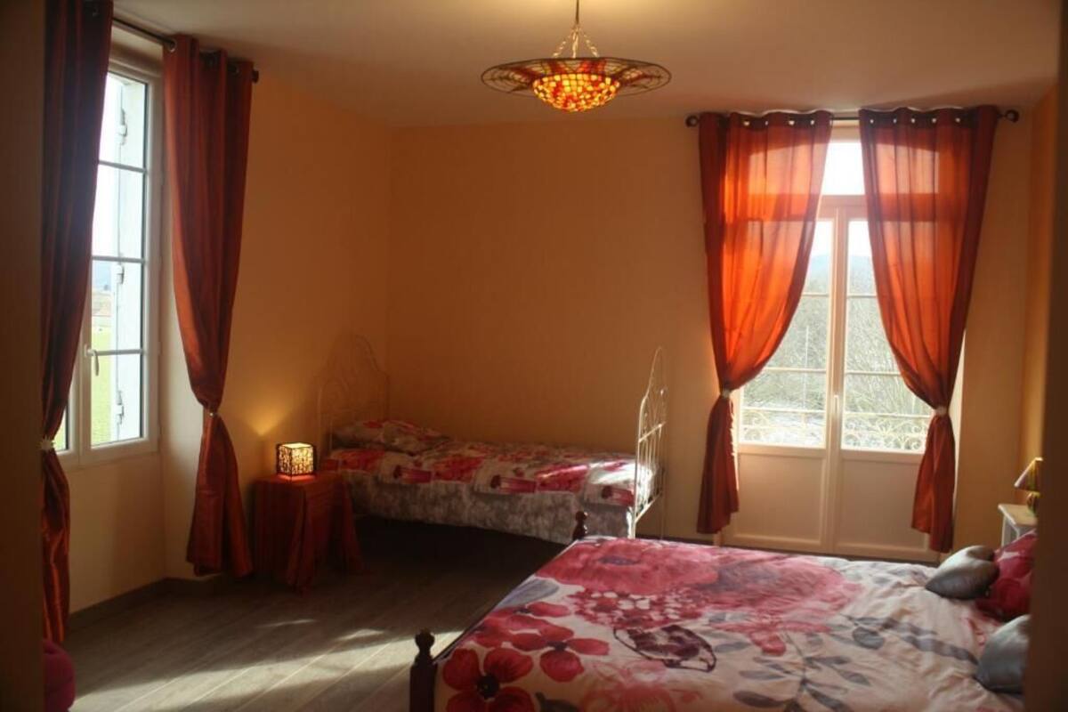 Une chambre avec deux lits, un lustre et une fenêtre avec des rideaux.