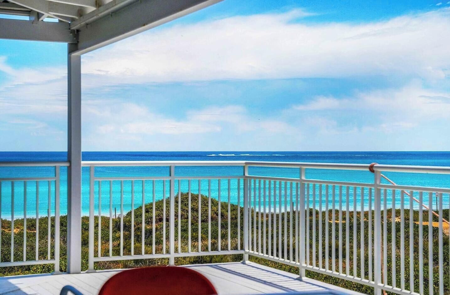 Un balcon donnant sur l’océan, avec une balustrade blanche.