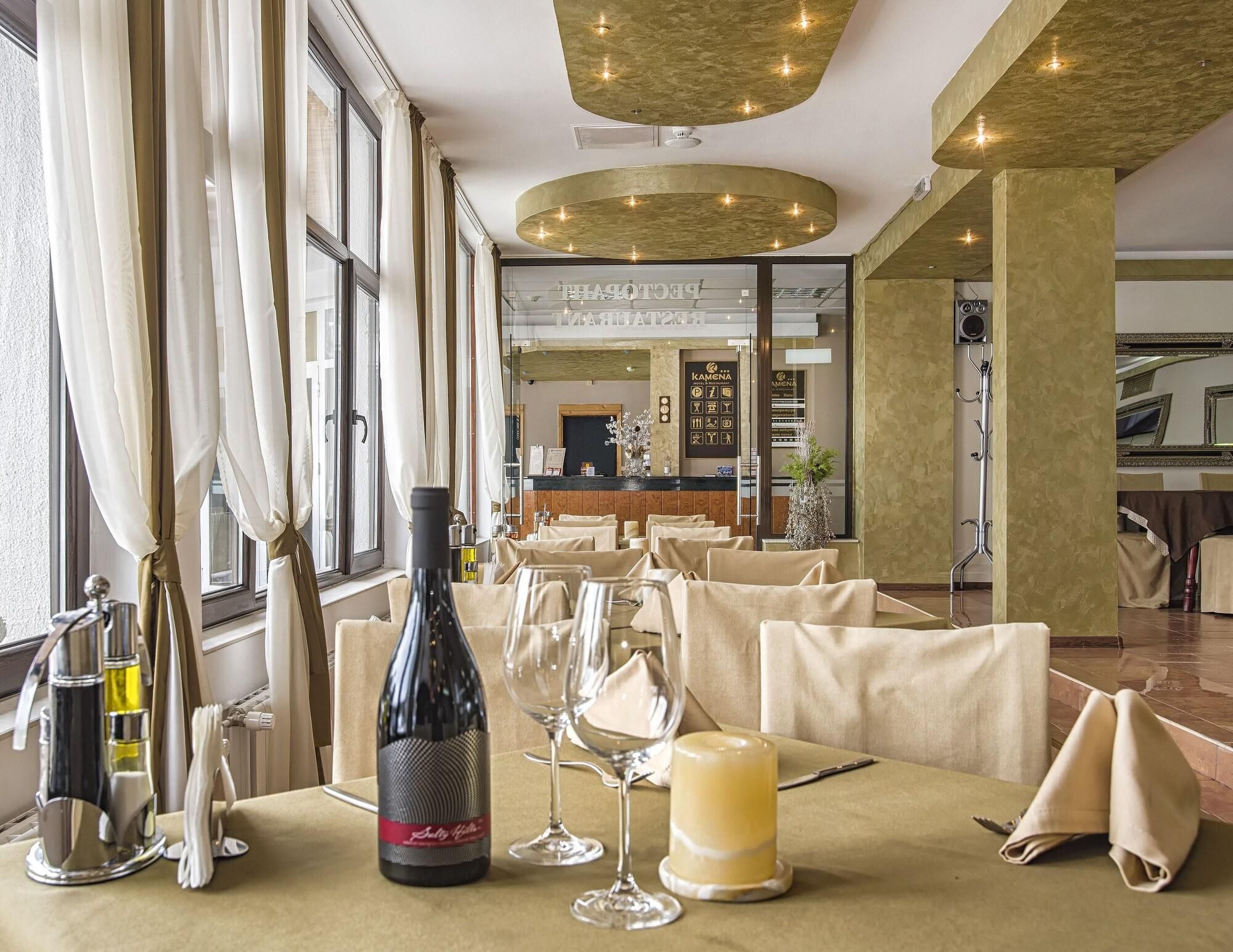 A restaurant interior with tables set for dining, a wine bottle, and glasses on the table.