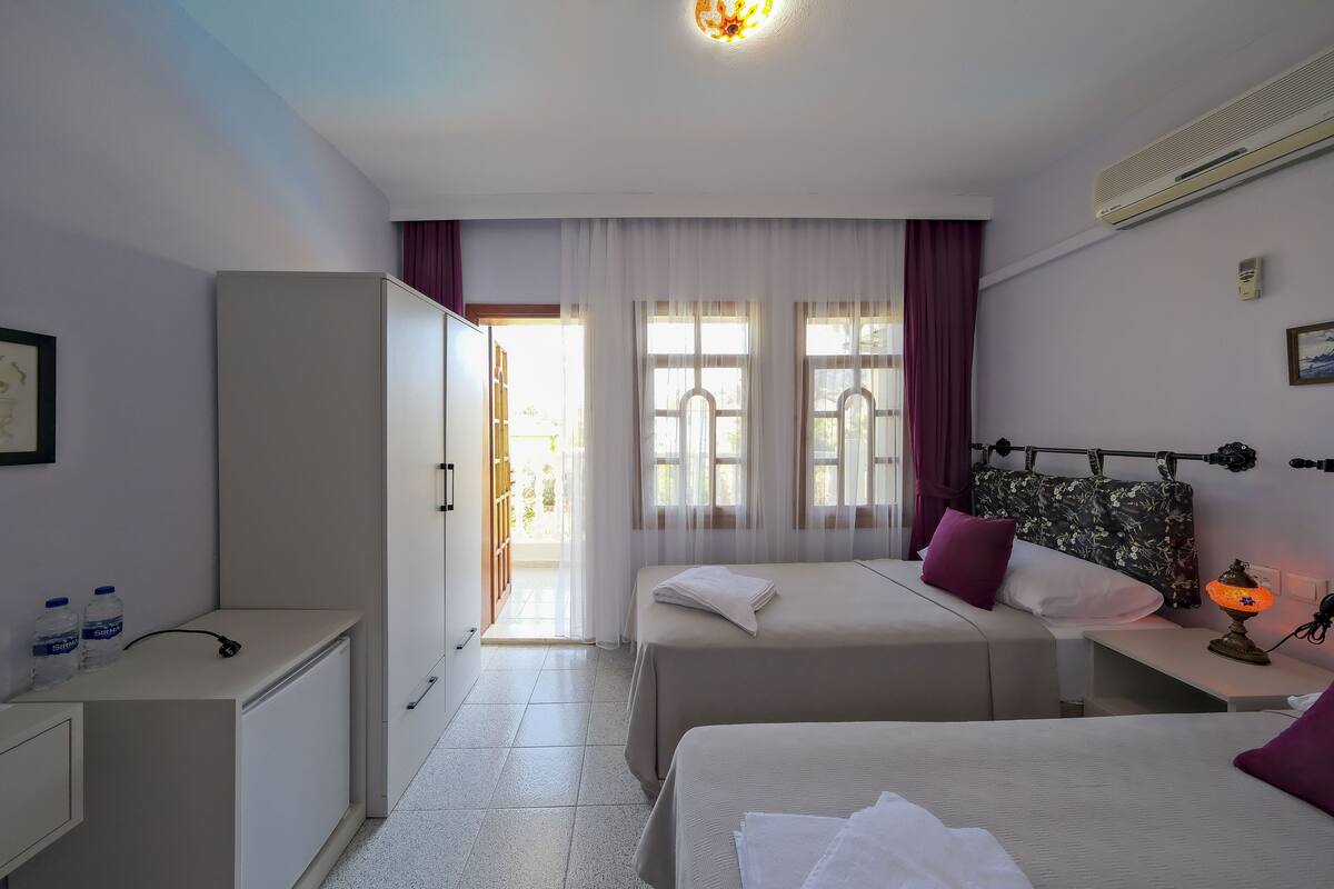 Une chambre d’hôtel avec deux lits, un bureau, une armoire et une fenêtre avec des rideaux.