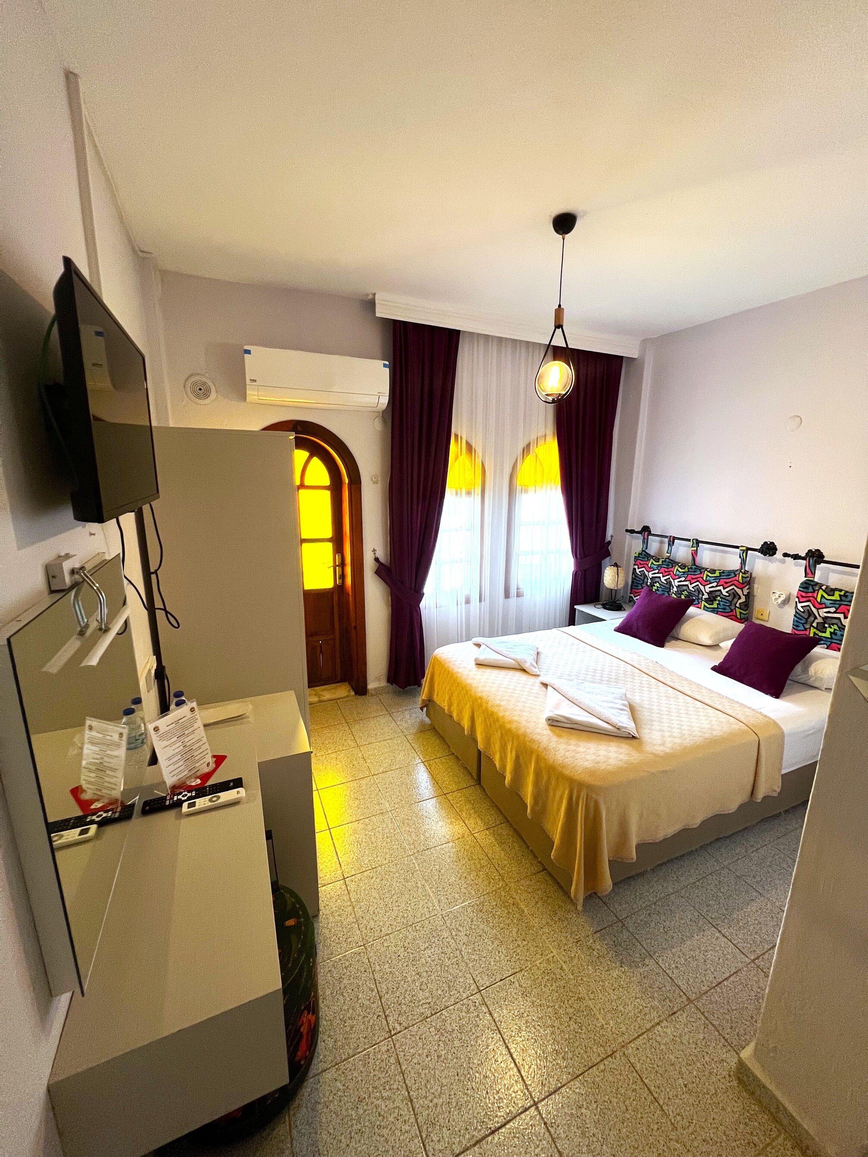 Une chambre d’hôtel équipée d’un lit, d’un bureau avec un miroir, d’une télévision et d’un appareil de climatisation.