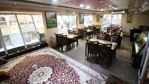 A restaurant with multiple tables and chairs, large windows, and a patterned carpet. - Maaeen Hotel (Dubai)