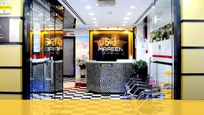 A hotel reception area with a checkered floor, a reception desk, and a glass wall. - Maaeen Hotel (Dubai)