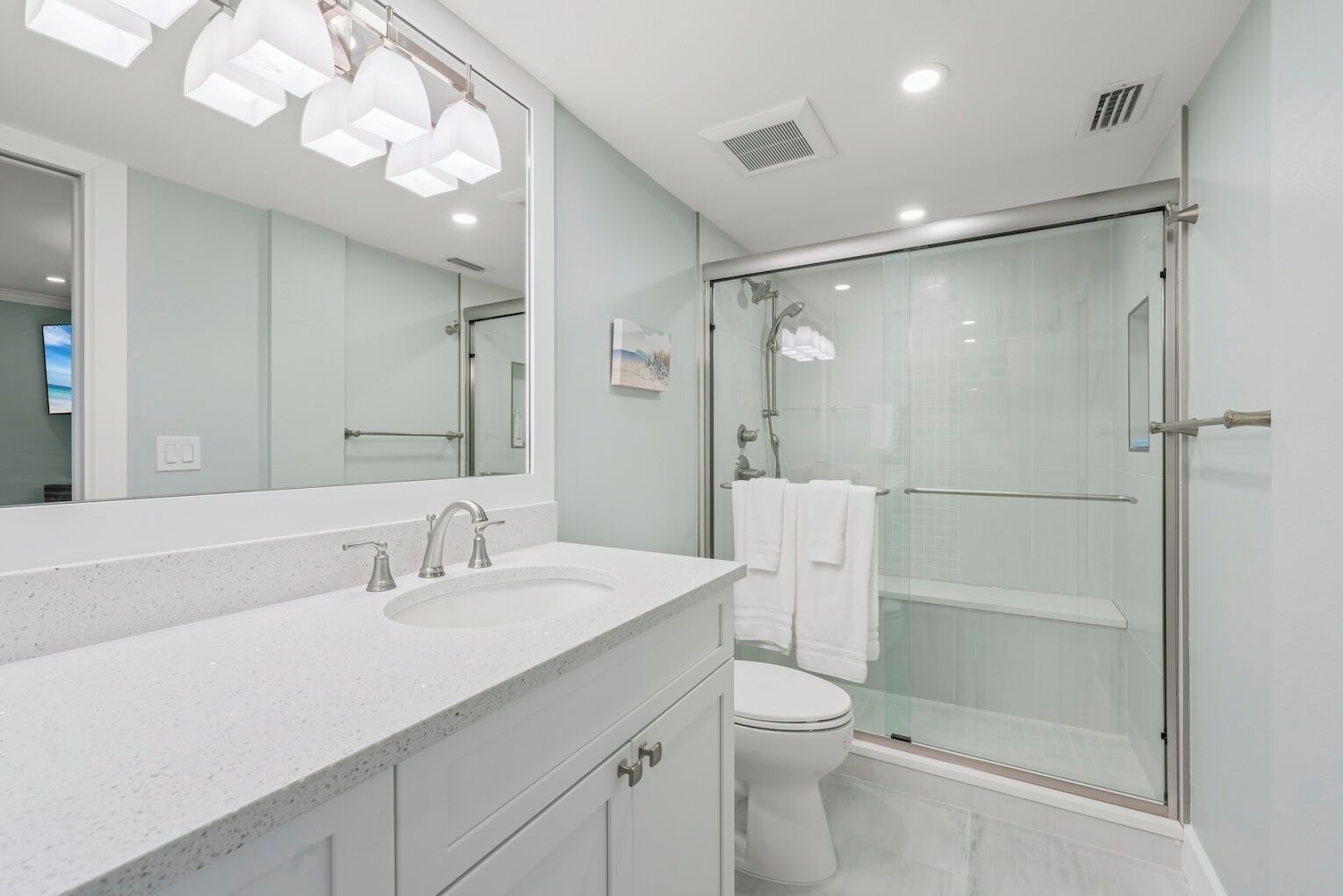 Une salle de bain moderne avec un double lavabo, un grand miroir et une douche à parois de verre.