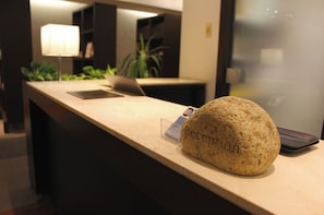 Un mostrador de recepción con una computadora portátil, una tableta y una piedra con la palabra 'Reception' grabada.