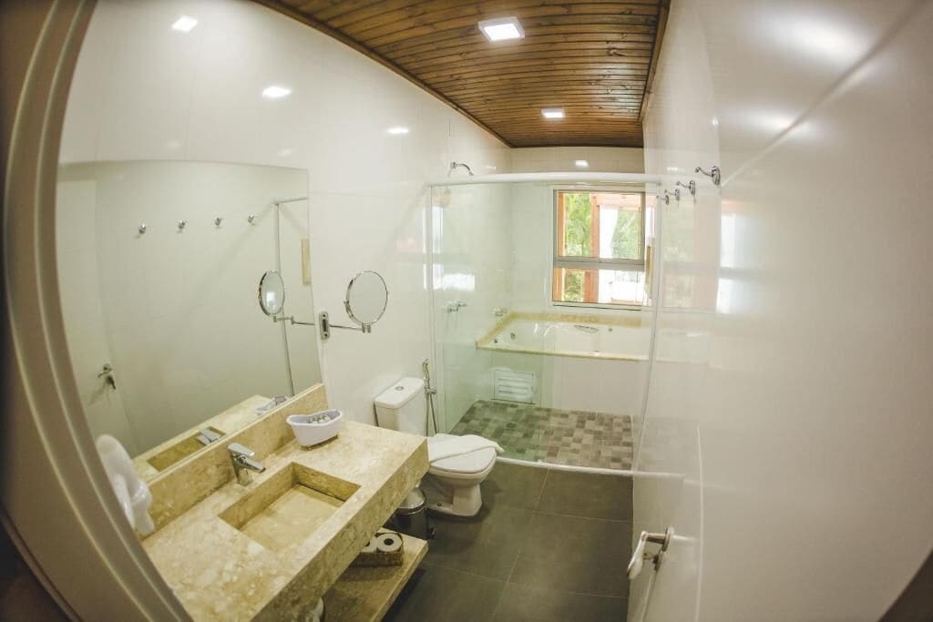 A modern bathroom with a glass-enclosed shower, a large mirror, and a separate toilet area.