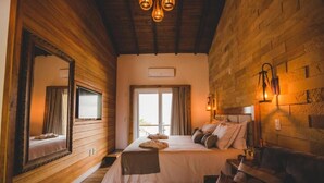 Une pièce chaleureuse avec un plafond en bois, un grand lit avec des oreillers, un miroir et une lampe fixée au mur.