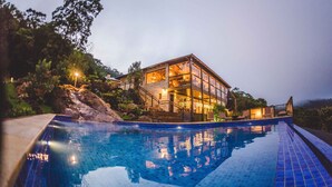 Un bâtiment moderne doté d’une façade en verre, d’une piscine et offrant une vue sur le paysage environnant.