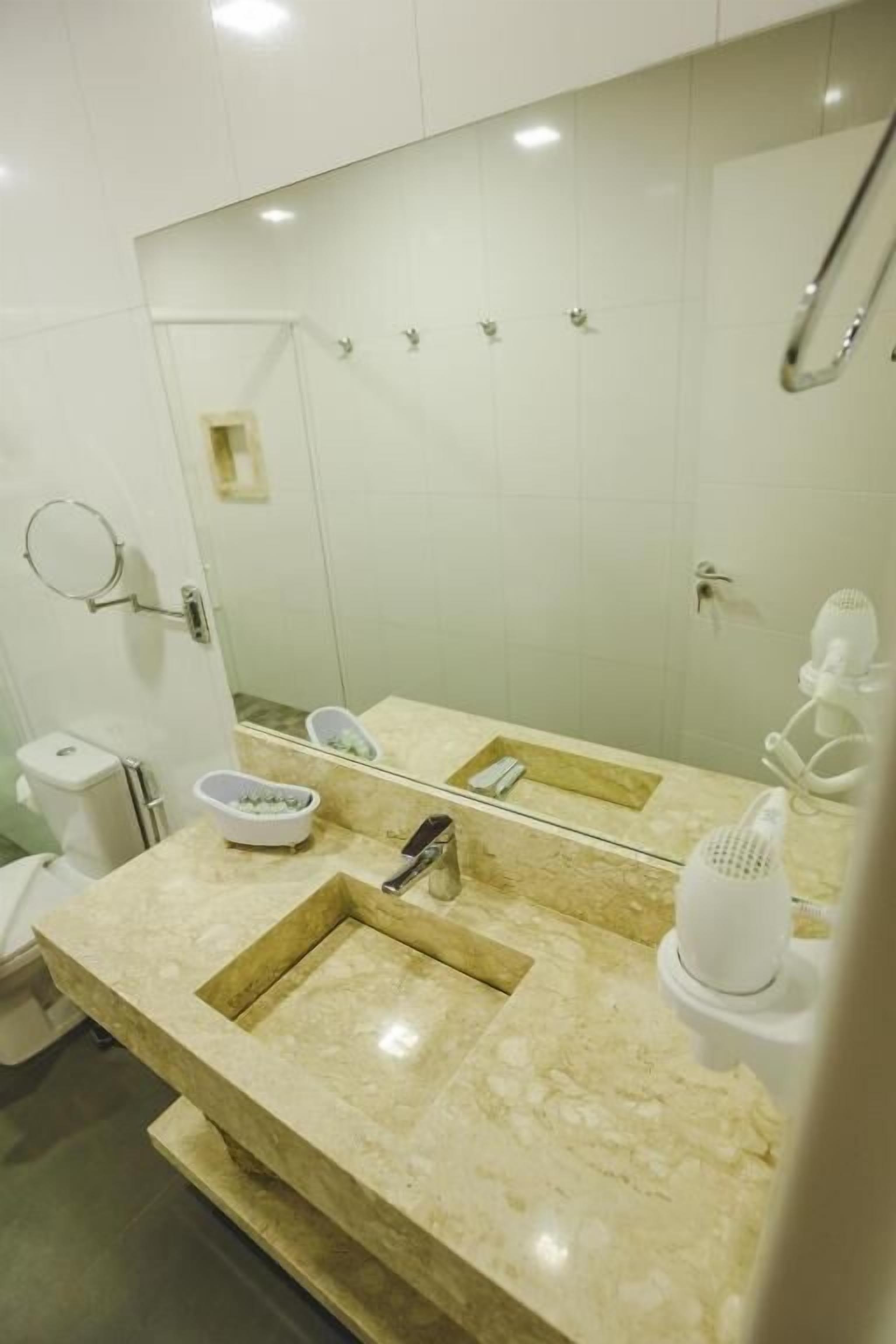 A modern bathroom with a large mirror, two sinks, a towel rack, and a shower area.