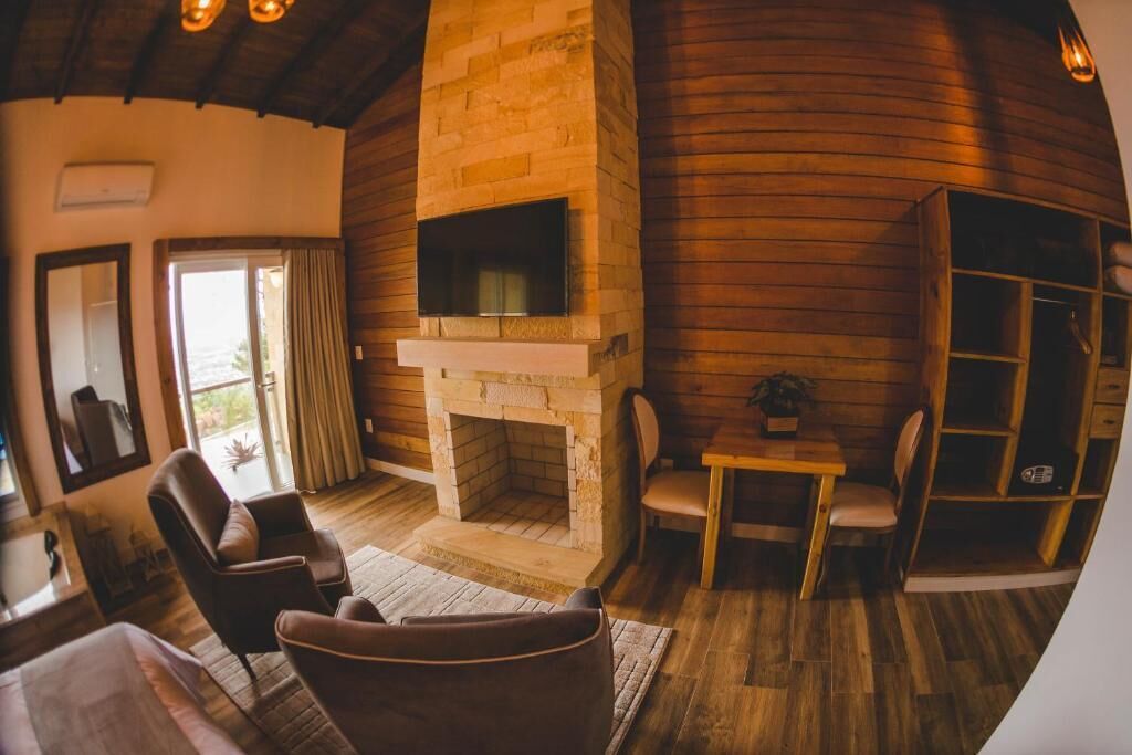 Ein gemütliches Wohnzimmer mit Kamin aus Stein, Holzwänden und bequemen Sitzmöglichkeiten.