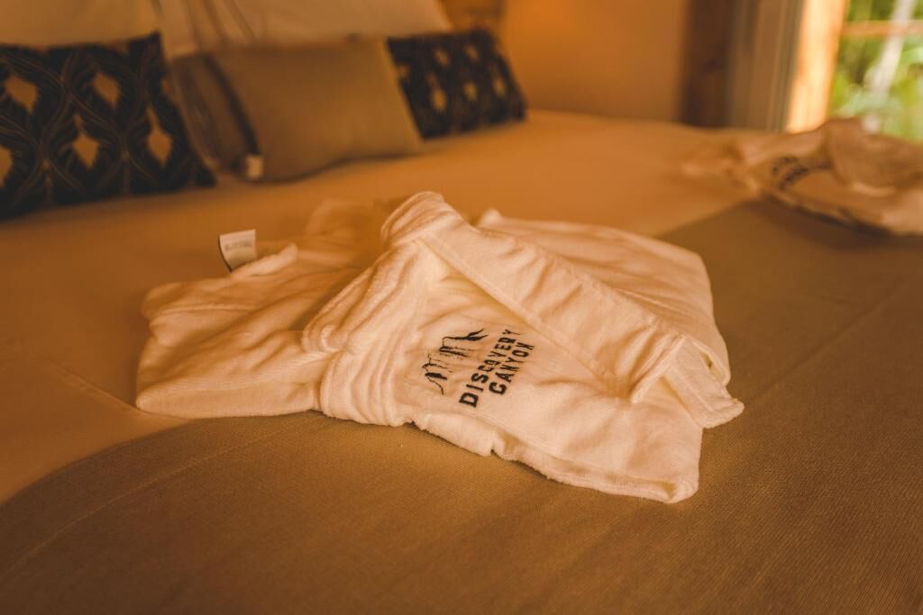 Ein ordentlich bezogenes Bett mit einem weißen Kopfkissen und einem weißen Kissenbezug mit einem Logo.