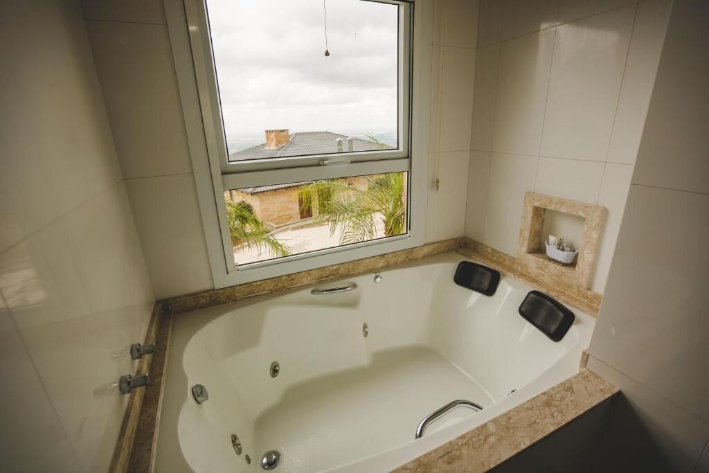 A bathroom with a large bathtub, a window, and a small shelf with toiletries.